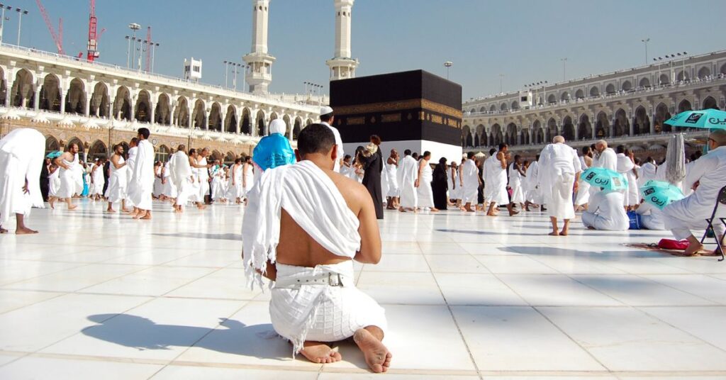 A photo of a person wearing white clothes and walking towards the Kaaba during Umrah pilgrimage.